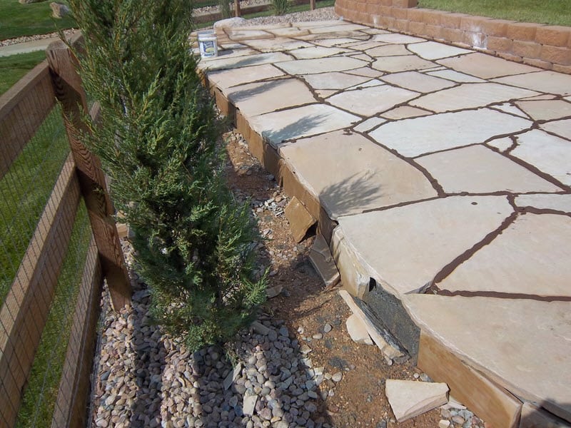A flagstone walkway alongside a fence